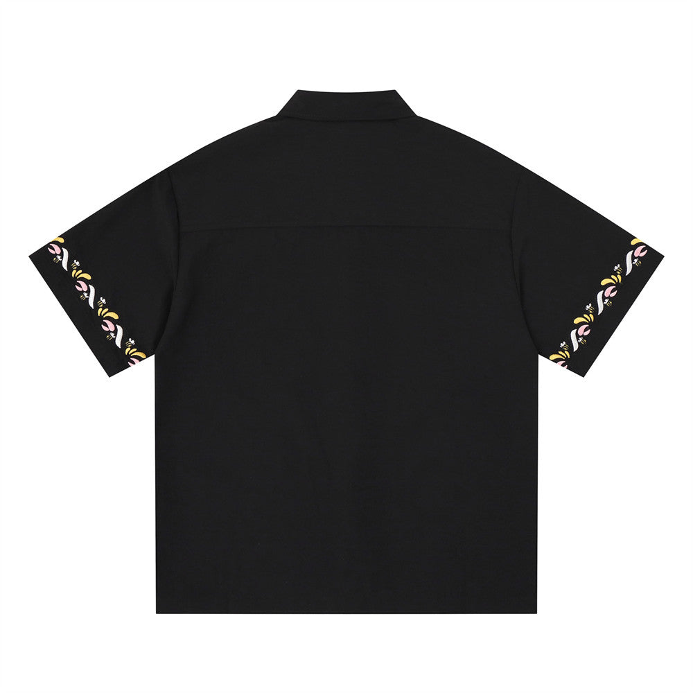 Black short sleeve button-up shirt back view with floral embroidery along both sleeve hems