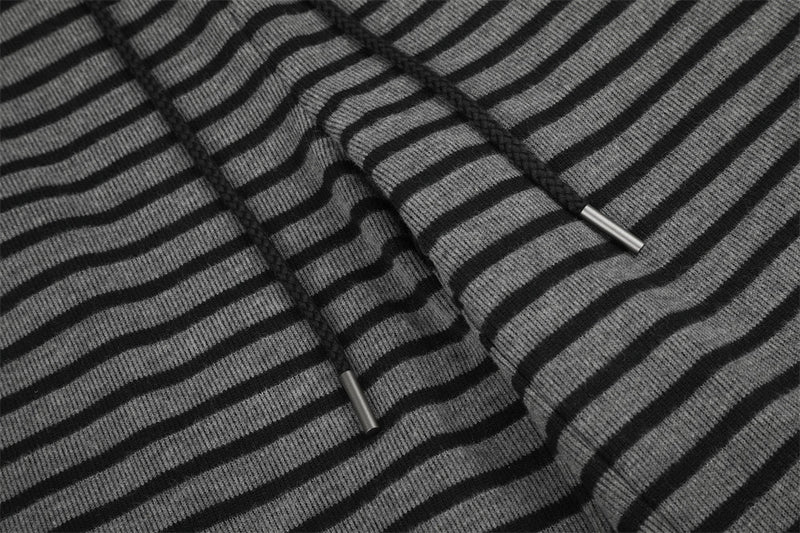 Drawstring ends on black and gray striped knit pants, close-up detail