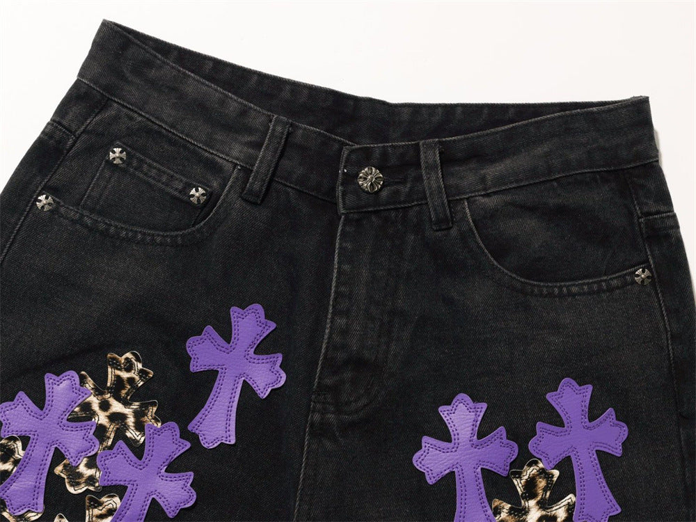 Close-up of black jeans front waistband, belt loops, and purple cross patches