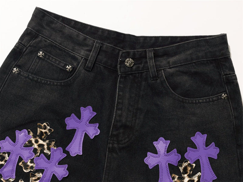 Close-up of black jeans front waistband, belt loops, and purple cross patches