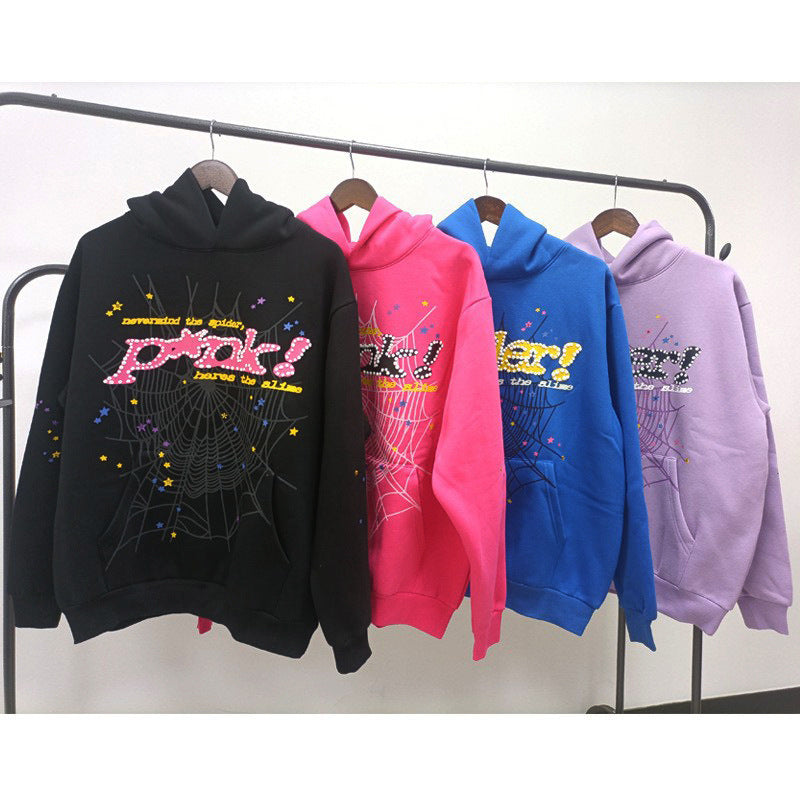 Four Sp5der hoodies hang on a rack in black, pink, blue, and lavender. Each features a striking web print design with colorful text, embodying the essence of the Sp5der Hoodie streetwear aesthetic.