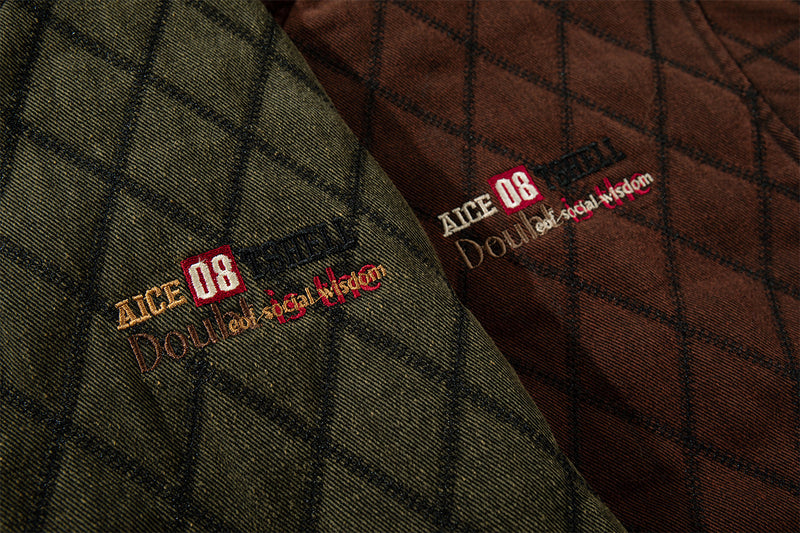 Close-up of embroidered chest branding on brown and olive quilted jacket fabric with a diamond pattern