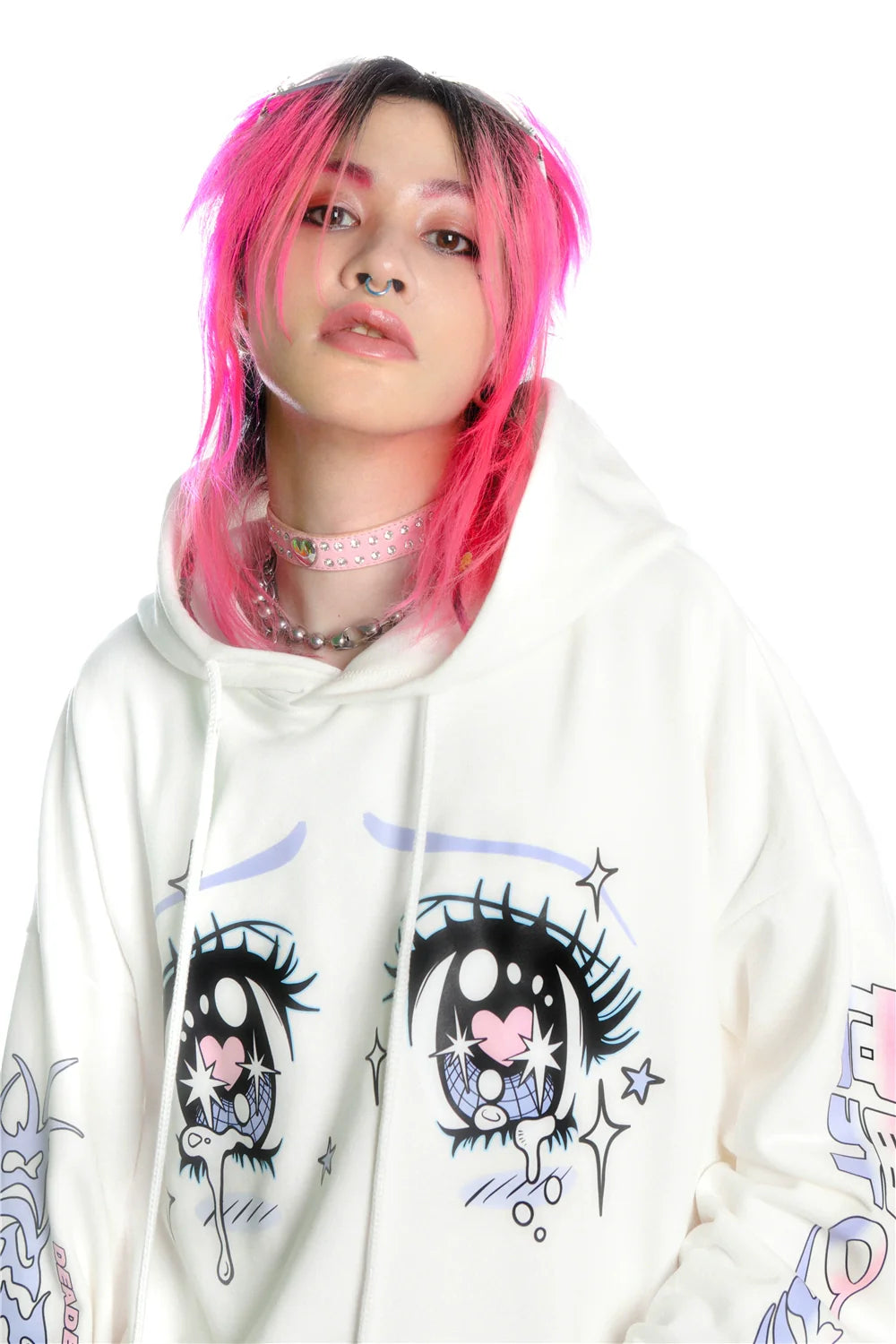 A person with bright pink hair stands against a white background wearing Seakoff's Kawaii Aesthetic Crying Eyes Hoodie, showcasing a pastel and dark anime style with sleeve graphics. Embracing streetwear fashion, they sport facial piercings and a pink spiked choker necklace.