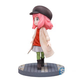 The Spy x Family Anya Forger PVC Figure is a cute chibi-style collectible statue, featuring Anya with pink hair in a black cap, orange top, light skirt, green tights, and black boots. It has an open beige coat and stands on a circular gray platform with subtle wooden texture. Height: 14 cm.