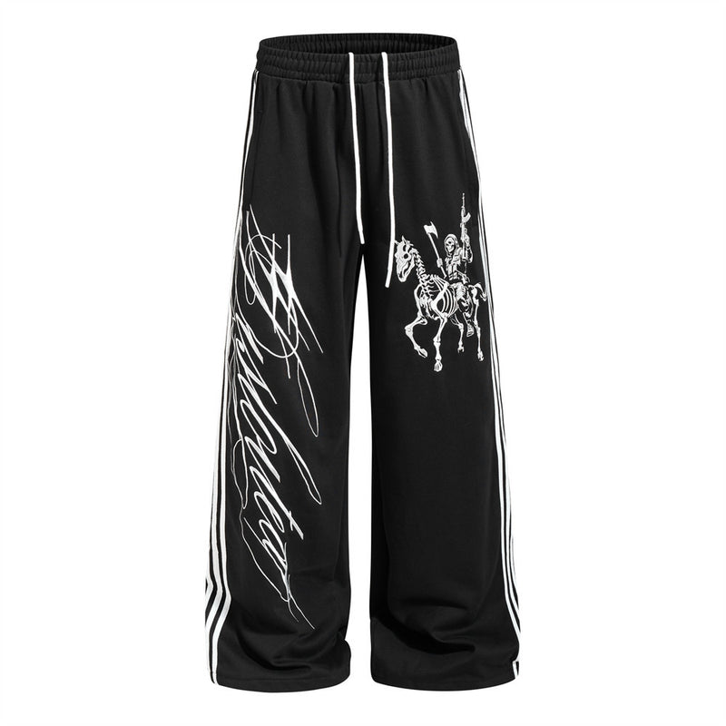 Wide-leg black track pants with skeleton rider graphic and three-stripe side tape detail