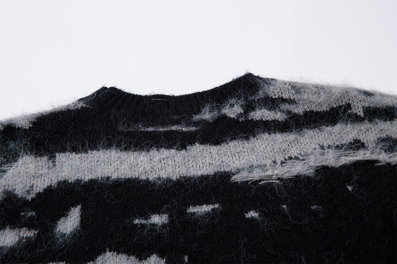 Close-up of the black ribbed crew neckline against the gray and black distressed stripe knit