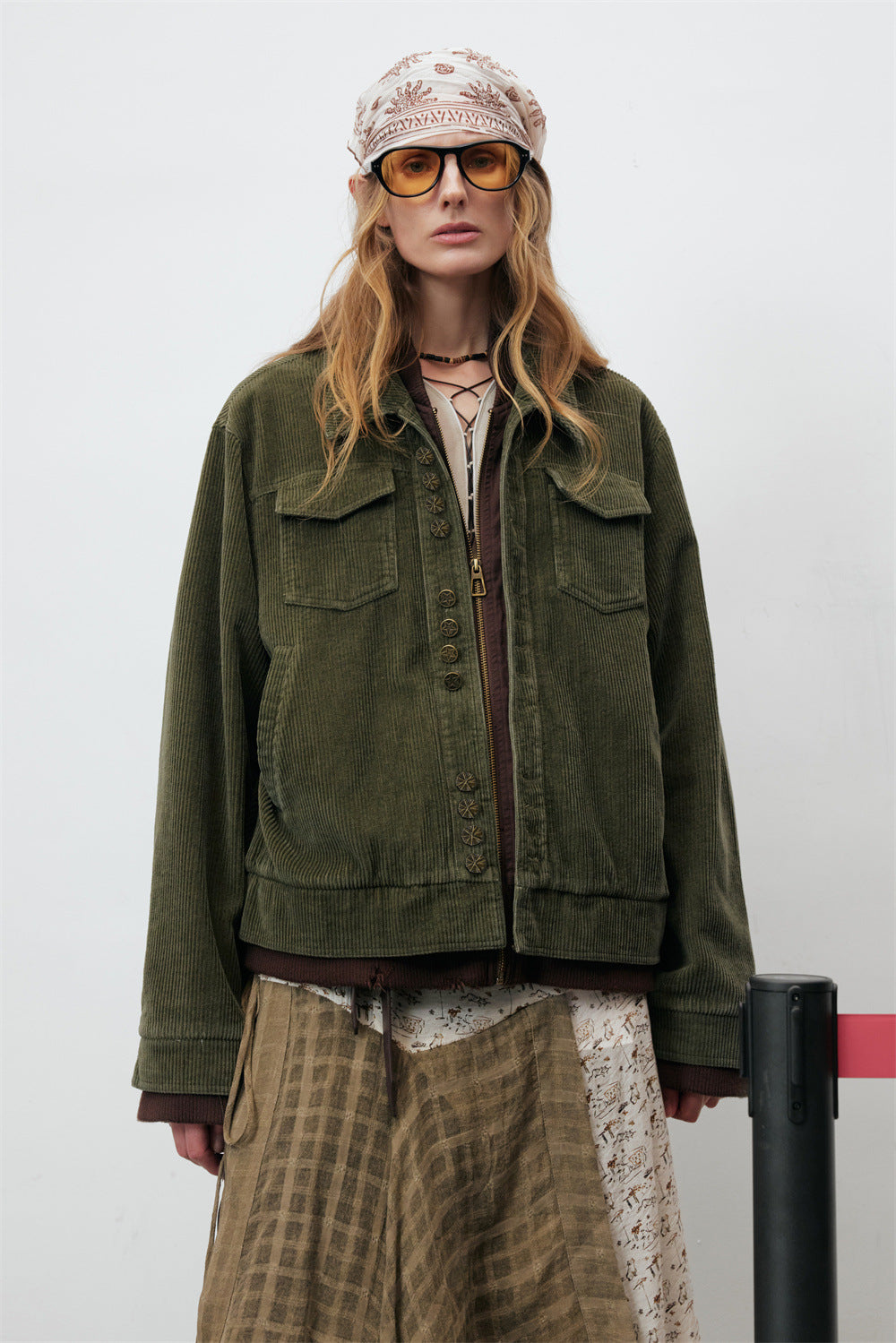 Men's oversized army green wide-wale corduroy jacket with metal buttons, brass zipper, and brown ribbed layered hem detail