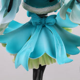 This close-up features the Hatsune Miku 1/7 Scale 28cm PVC Figure by Hatsune Miku, showcasing her in an elegant pose with flowing hair and a blue dress with a large bow. The layered dress flows against a gray background, while her black legs peek out beneath, enhancing this collectible&