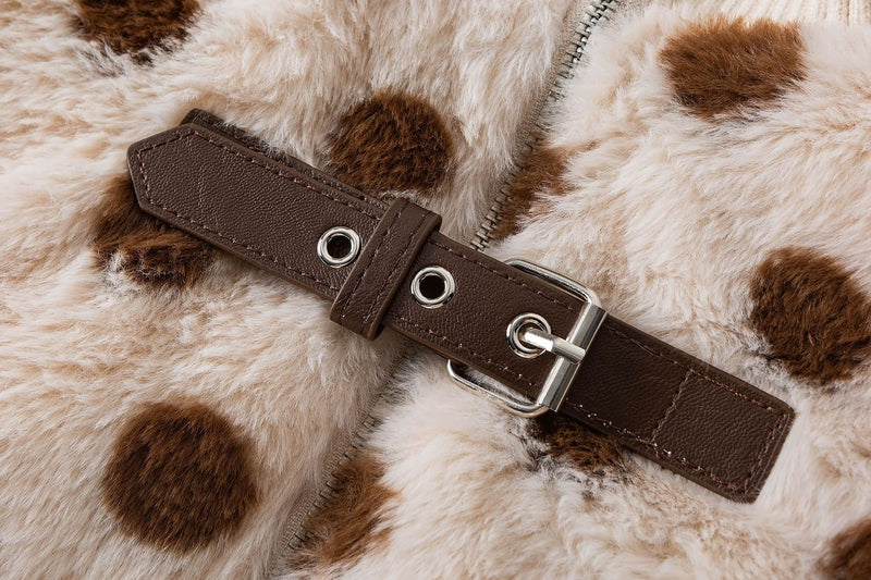 Close-up of the brown strap fastening with metal hardware on a cream polka dot faux shearling jacket