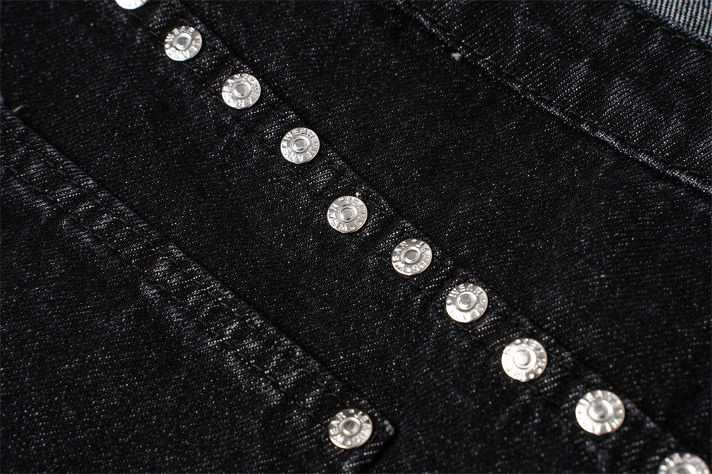 Close-up of silver studs arranged along the back yoke of black denim jeans