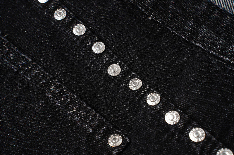 Close-up of silver studs arranged along the back yoke of black denim jeans