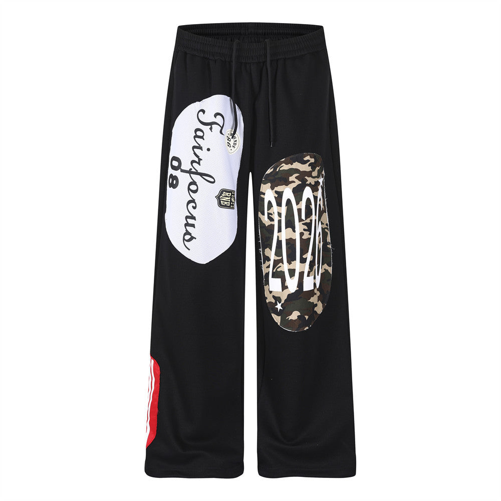 Black wide-leg sweatpants with white mesh script patchwork and camouflage oval appliqué on the front leg