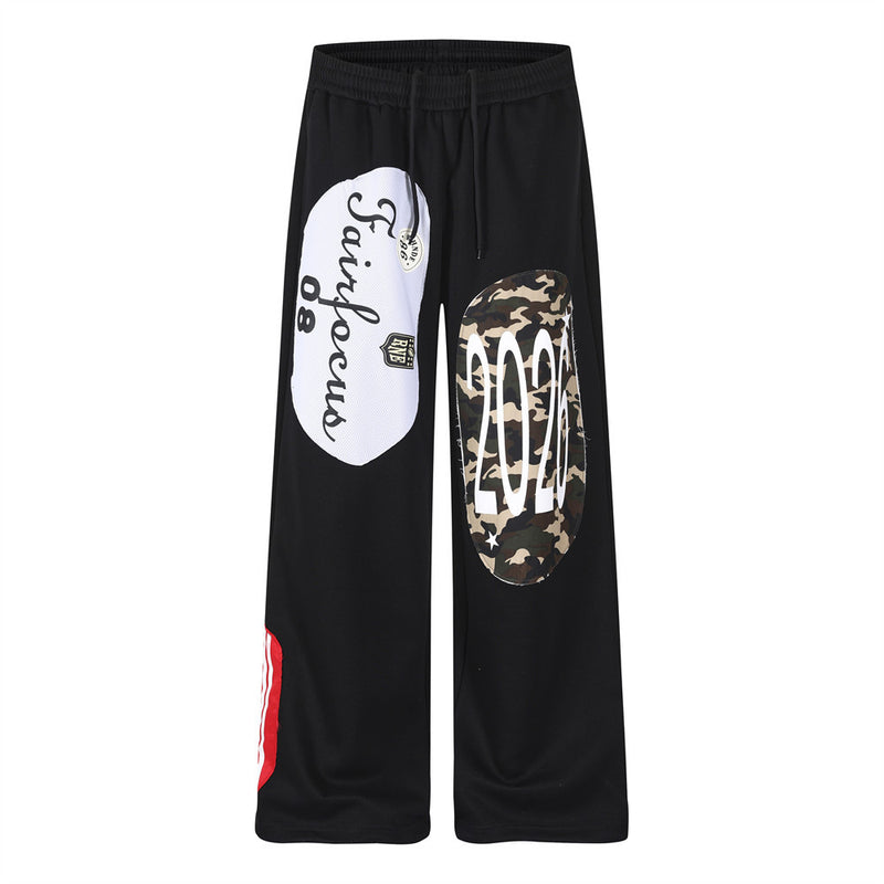 Black wide-leg sweatpants with white mesh script patchwork and camouflage oval appliqué on the front leg