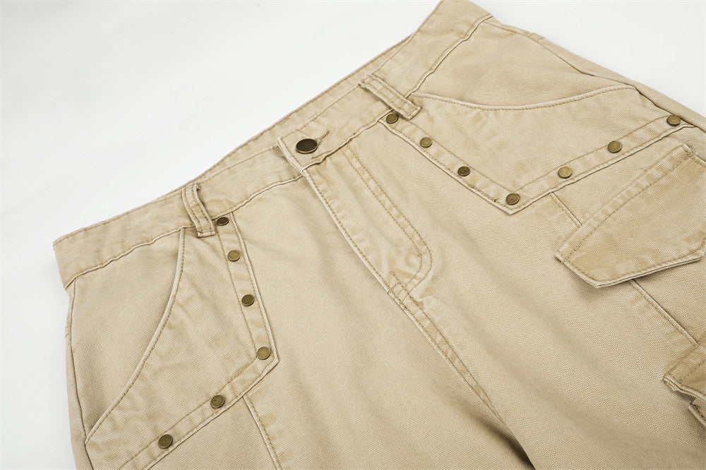 Close-up of beige cargo pants waist with rivets, belt loops, and front pocket stitching