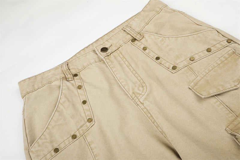 Close-up of beige cargo pants waist with rivets, belt loops, and front pocket stitching