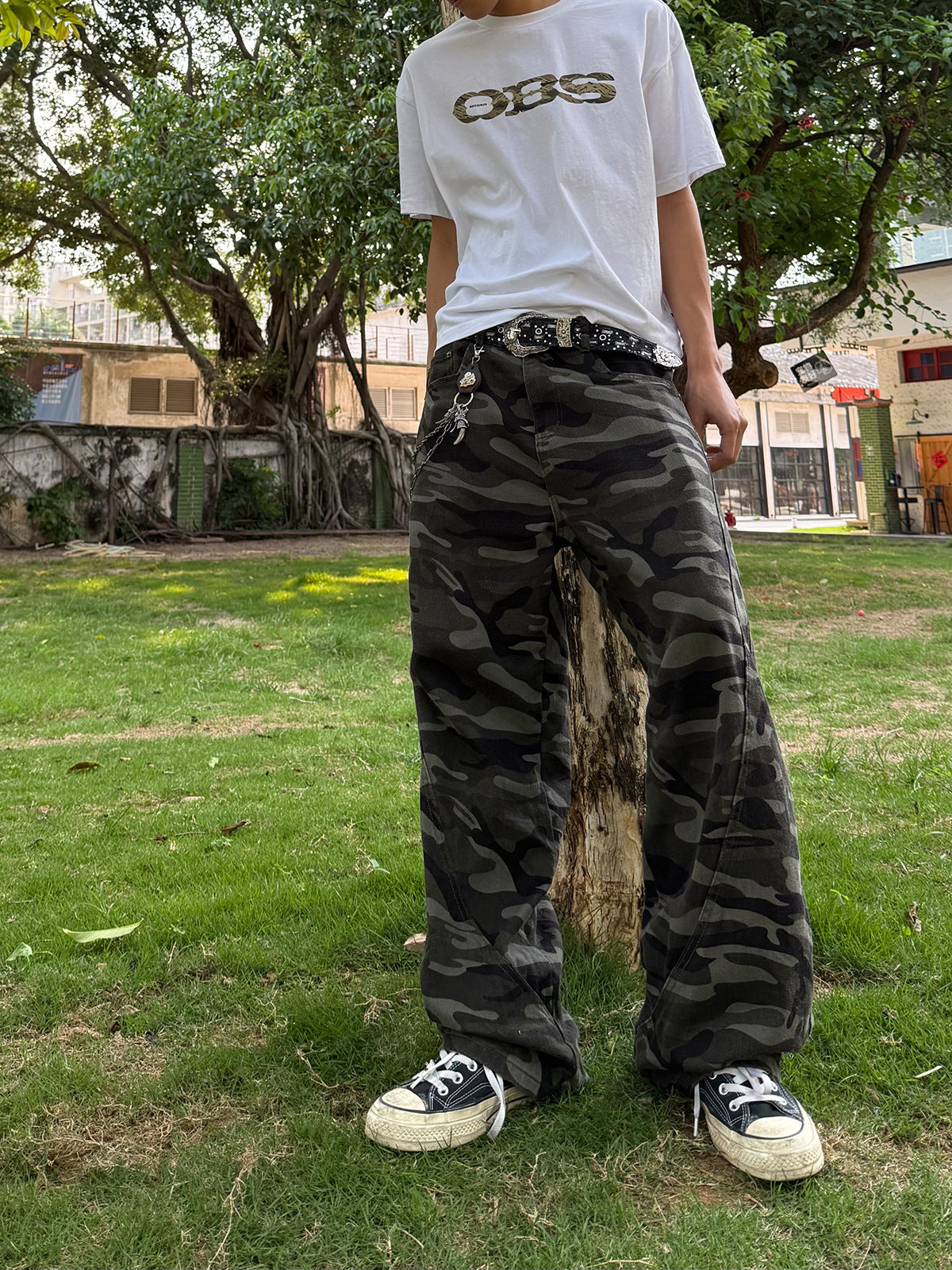 Pantalon cargo camouflage foncé à jambes larges, finition vintage délavée, porté avec un t-shirt court et des bottines noires