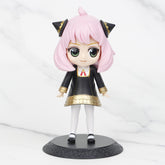 This chibi-style Spy × Family figure, ideal for anime collectors, showcases pink hair, green eyes, black cat ears, a black dress with gold accents and a red tie. It stands on a round base with white stockings and black shoes against a marble backdrop. Part of the 15cm Anya, Loid & Yor PVC set.