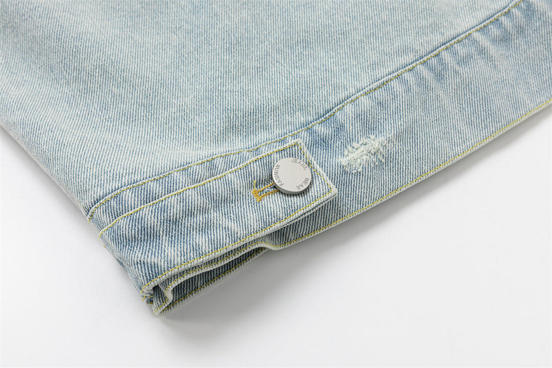 Close-up of the lower jacket hem showing a buttoned adjustment tab and distressed denim