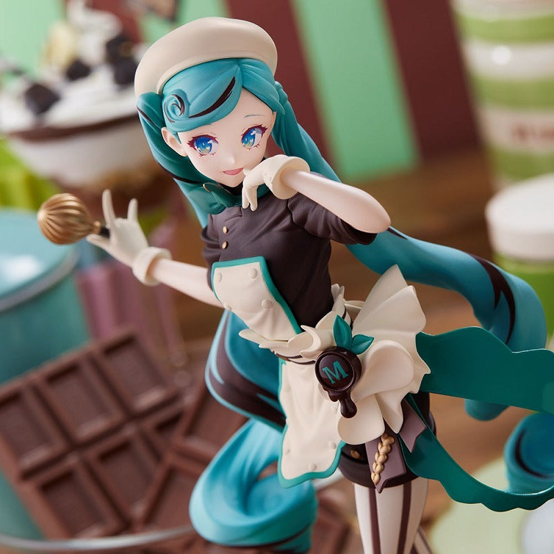 The Hatsune Miku Black Chocolate Pastry Chef 21cm PVC Figure is a detailed collectible featuring a blue-haired anime-style chef in a white apron and hat, holding a whisk. The backdrop is filled with kitchen-themed elements like chocolate bars, making it perfect for any anime enthusiast.