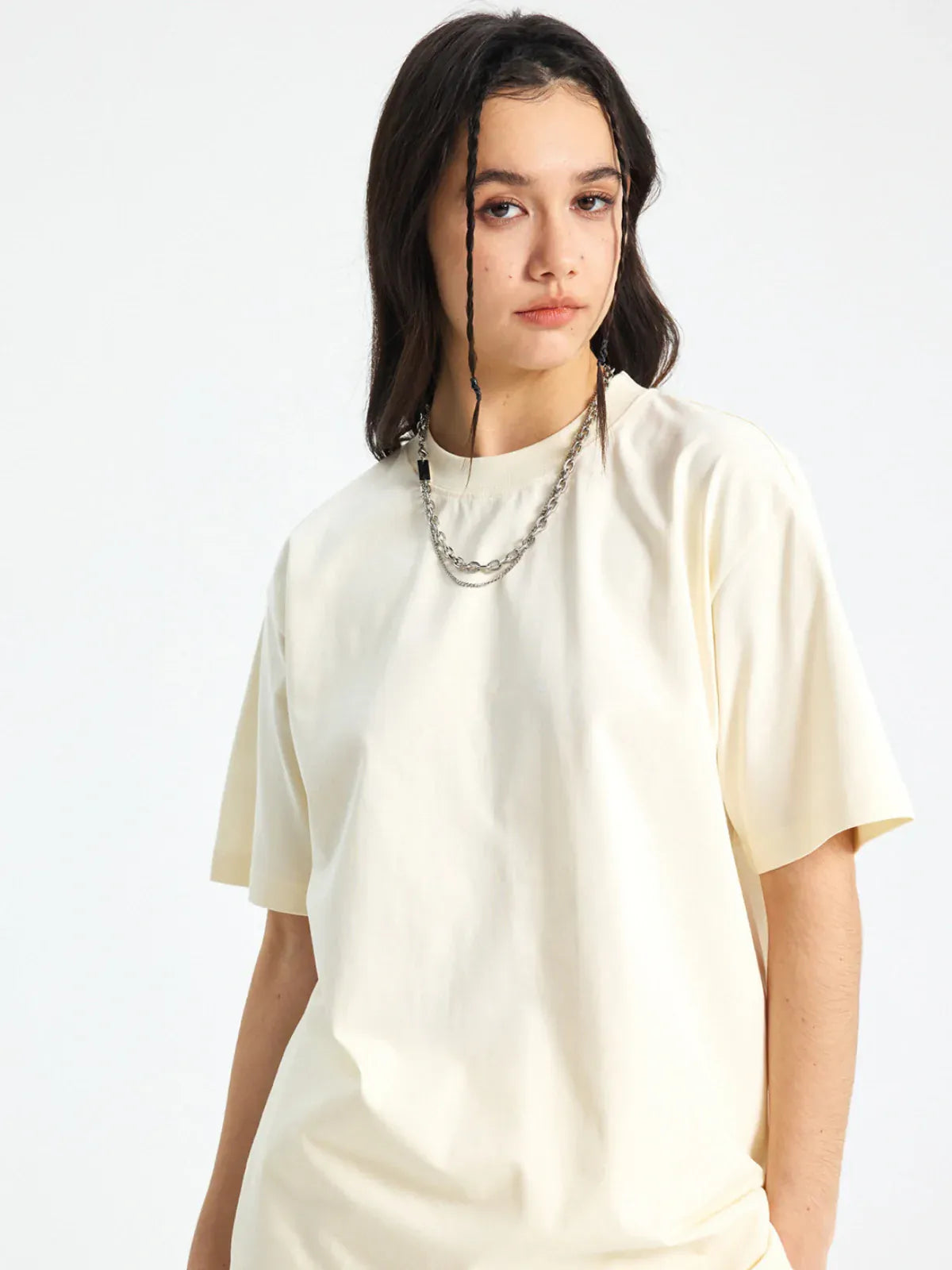 A person with long dark hair and two face-framing braids wears the Custom Anime Character Cream T-Shirt—Personalized 230GSM 100% Cotton Tee—paired with a chain necklace, standing against a plain white background.