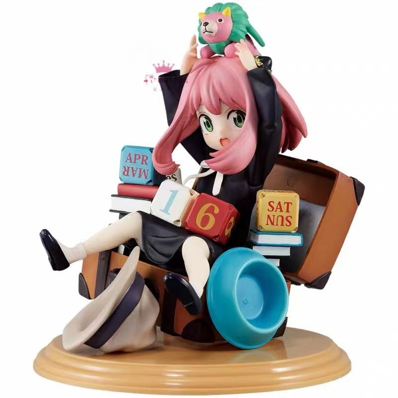 The Spy x Family Anya Forger PVC Figure features a pink-haired girl in a black dress sitting on a chair with books, holding a green and pink lion toy. A blue bowl and gray hat accompany this 16 cm collectible, capturing an endearing scene with intricate detail.