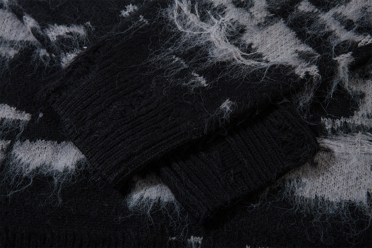 Close-up of a black ribbed sweater cuff over the fuzzy distressed black and gray knit pattern