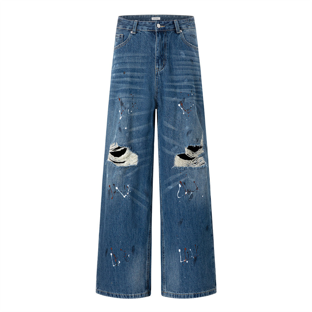 Men's wide-leg distressed blue denim jeans with large knee rips and white and red paint splatter detailing, front and back vi