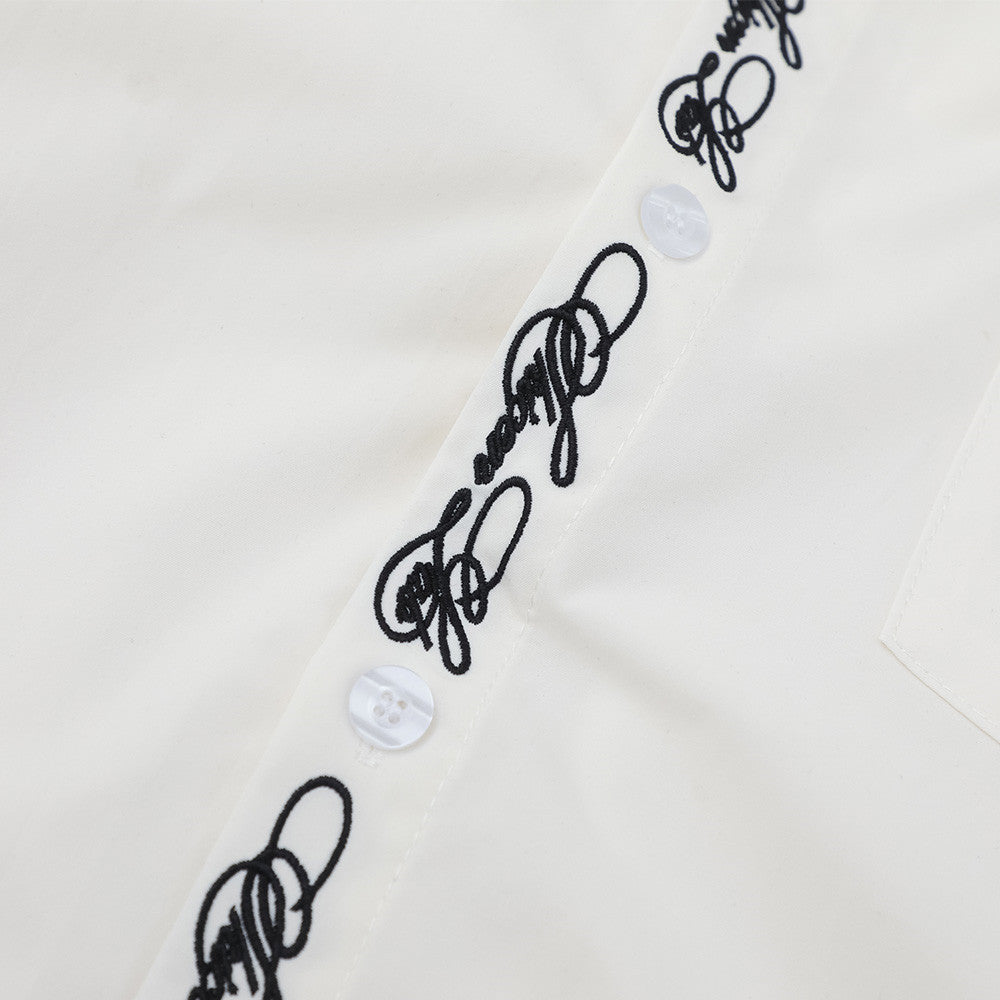 Close-up of white shirt placket with script embroidery and translucent buttons