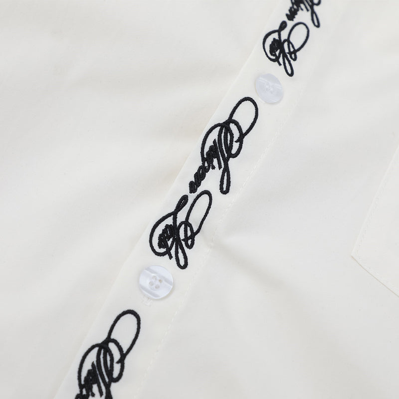 Close-up of white shirt placket with script embroidery and translucent buttons