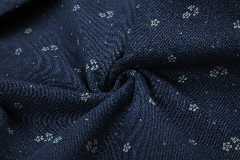 Close-up of dark blue denim fabric with small floral print and twisted fold