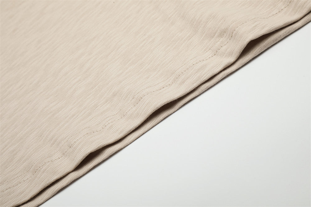Beige tee sleeve and hem close-up showing smooth fabric and stitching
