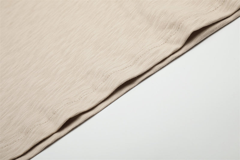 Beige tee sleeve and hem close-up showing smooth fabric and stitching