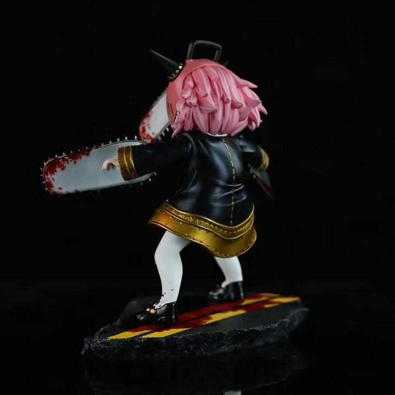 The Chainsaw Man Anya Forger PVC Figure, part of the Spy × Family collection, showcases a pink-haired Anya in a striking black and gold outfit with white pants, wielding a bloody chainsaw. She stands on a textured black base with red and yellow markings against a solid black backdrop.