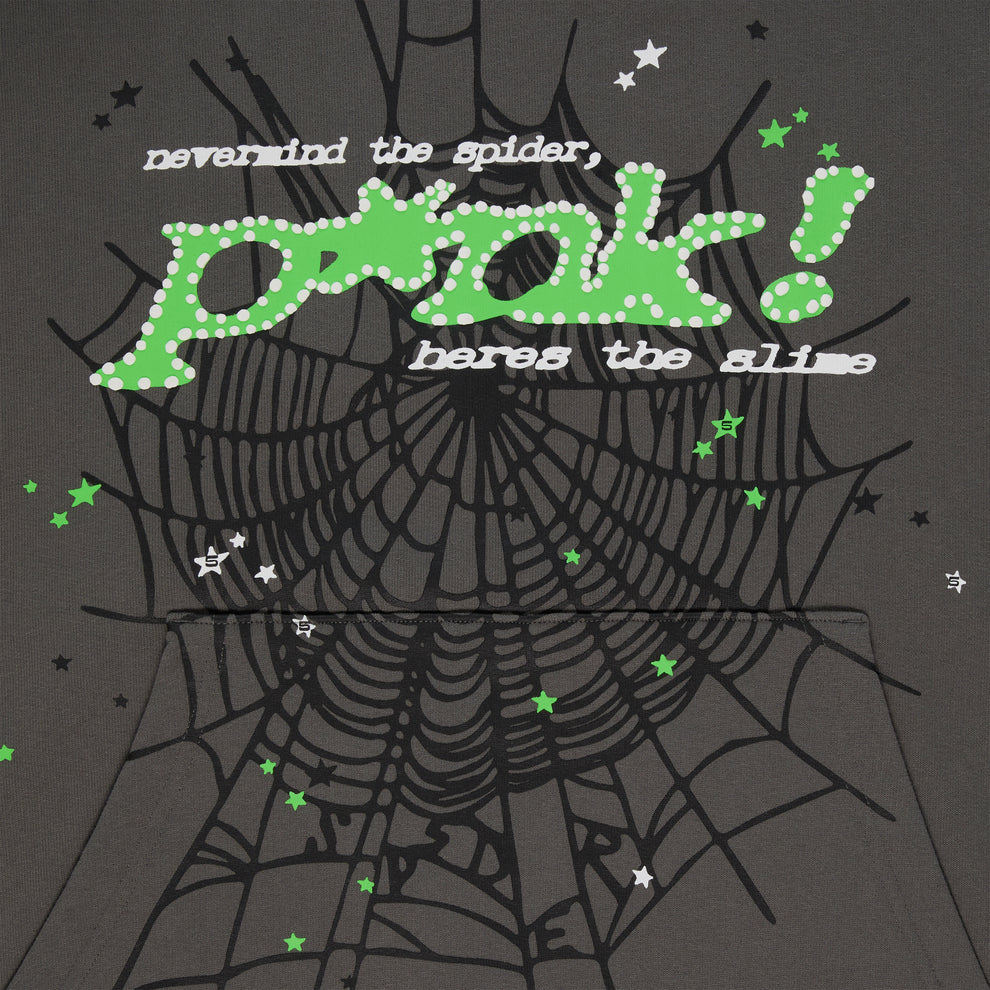 A black background with a large spiderweb and green, white stars highlights the Sp5der “P!nk! Hares the Slime” Hoodie—an olive green 440GSM heavyweight cotton fleece pullover styled like bold streetwear.