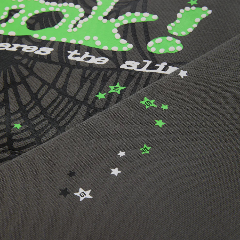 Close-up of the Sp5der “P!nk! Hares the Slime” Hoodie in olive green 440GSM heavyweight fleece—features green and white text, polka dots, web-like designs, scattered stars, and signature S marks for iconic streetwear style.