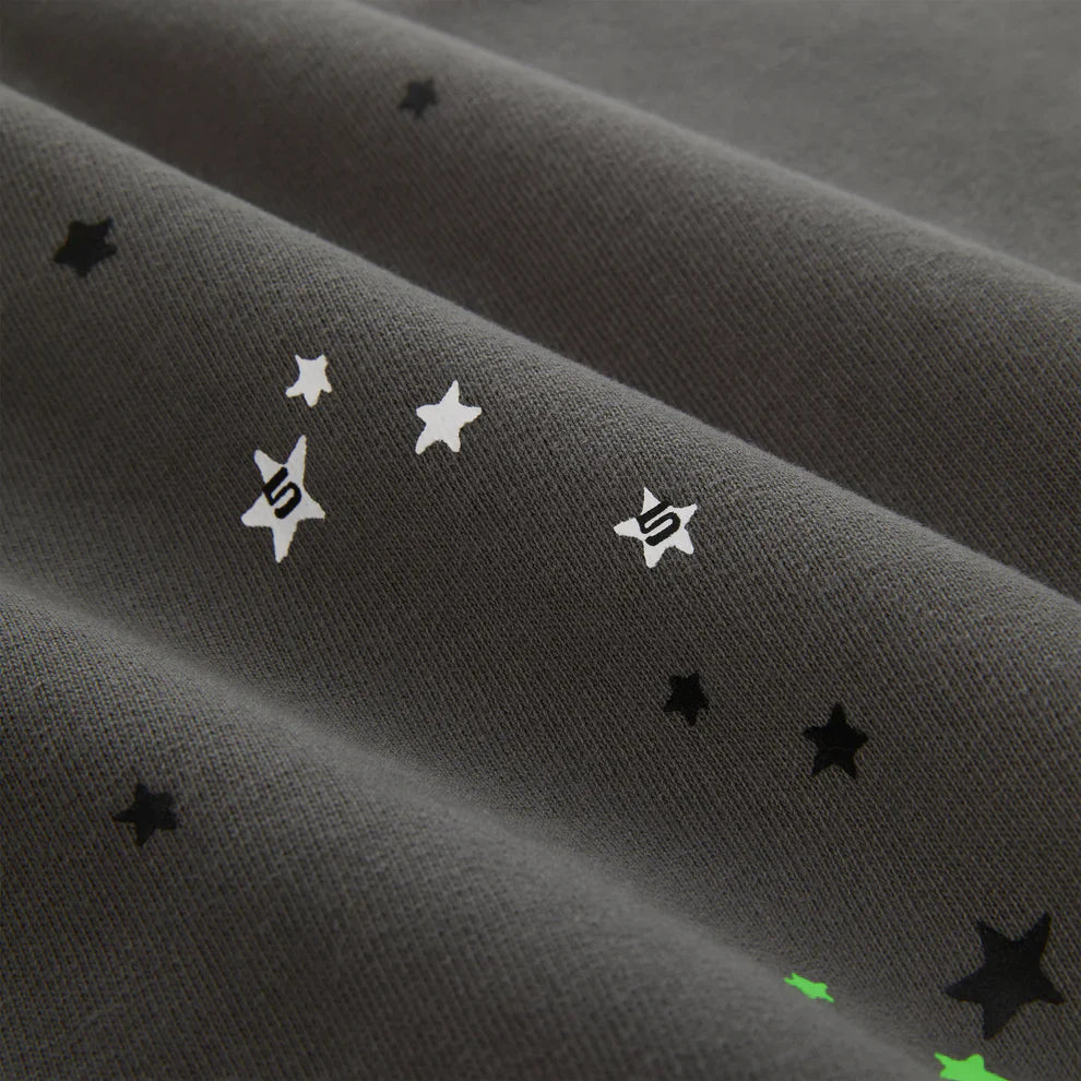Close-up of heavyweight 440GSM cotton fleece with black, white, and green star patterns and stylized S symbols, evoking classic streetwear—reminiscent of the Sp5der “P!nk! Hares the Slime” Olive Green Spider-Web Pullover Hoodie.