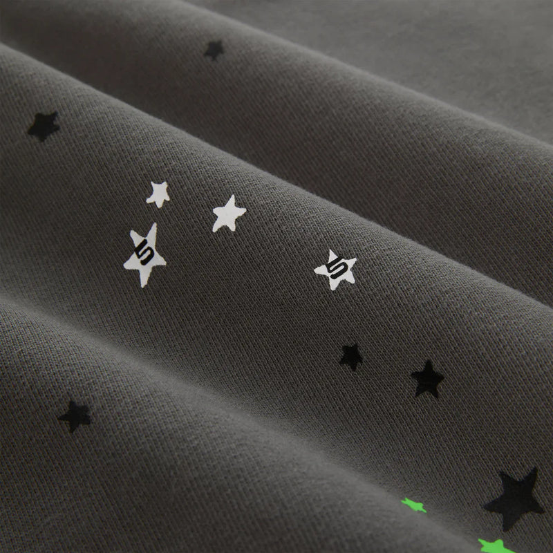 Close-up of heavyweight 440GSM cotton fleece with black, white, and green star patterns and stylized S symbols, evoking classic streetwear—reminiscent of the Sp5der “P!nk! Hares the Slime” Olive Green Spider-Web Pullover Hoodie.