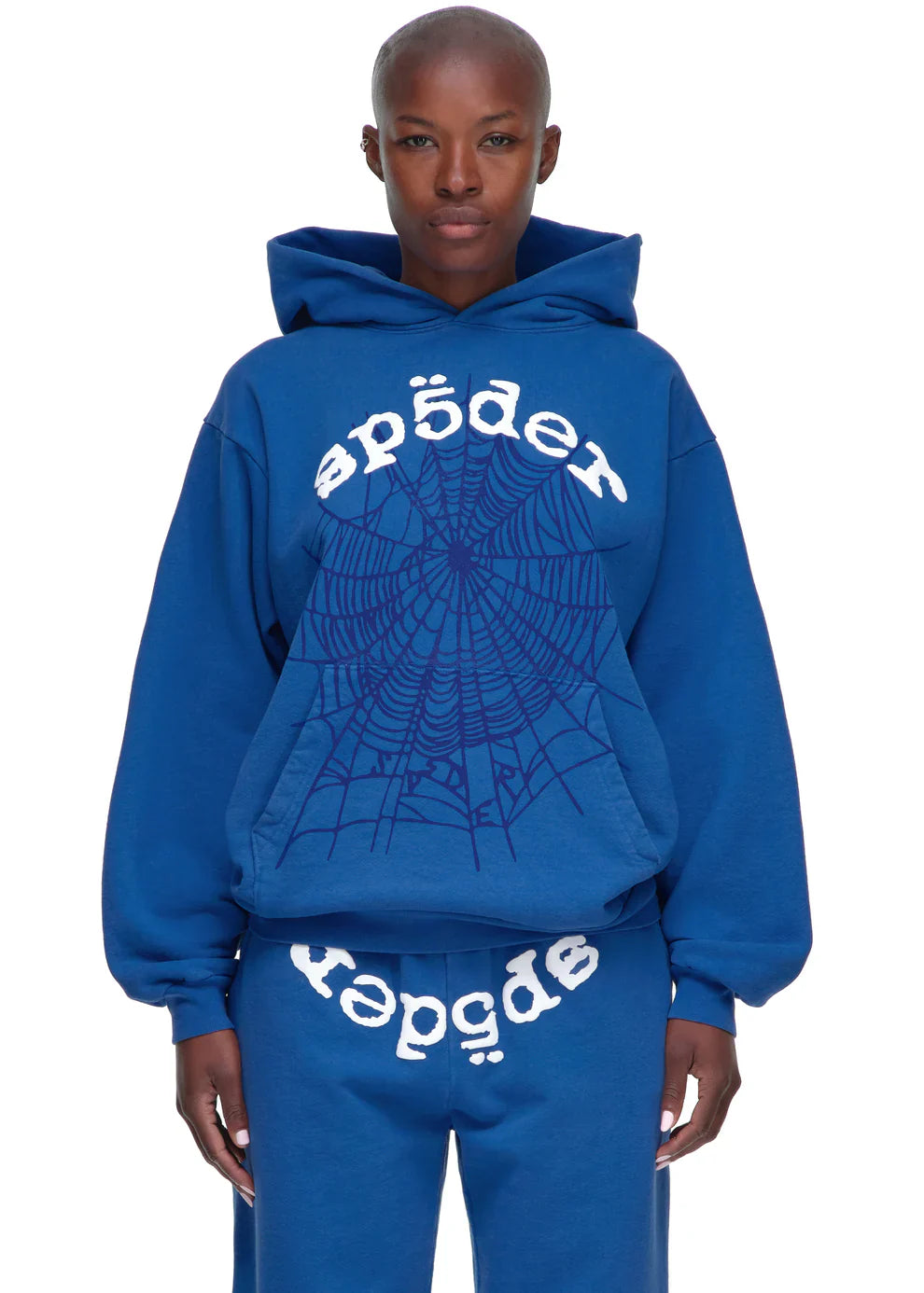 A person wears the Sp5der OG Web Hoodie 440GSM in royal blue—a heavyweight streetwear sweatshirt with a large white spiderweb and "sp5der" print—paired with matching sweatpants featuring the same graphic.