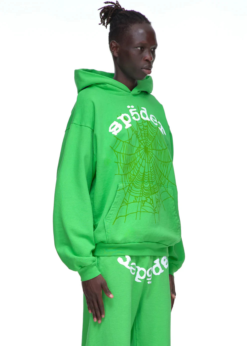 A person wears the Sp5der “Web Core” Hoodie – Neon Green 440GSM Heavyweight Oversized Streetwear Pullover and matching pants with sp5der text and a spiderweb graphic, standing against a plain white background.
