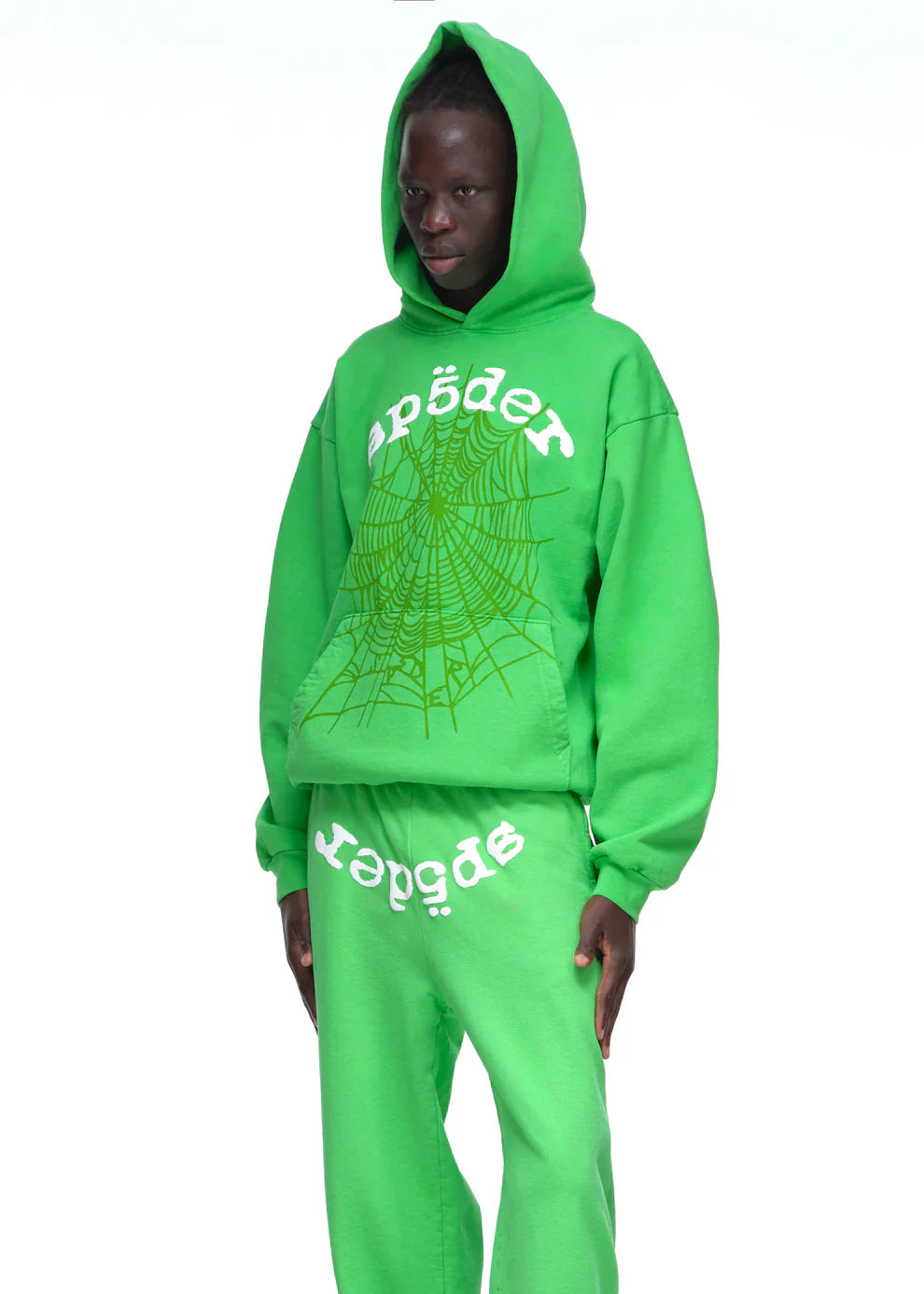 Wearing a neon green Sp5der “Web Core” Hoodie – 440GSM heavyweight oversized streetwear pullover, and matching sweatpants with white spider text and web graphic, a person stands against a plain white background.