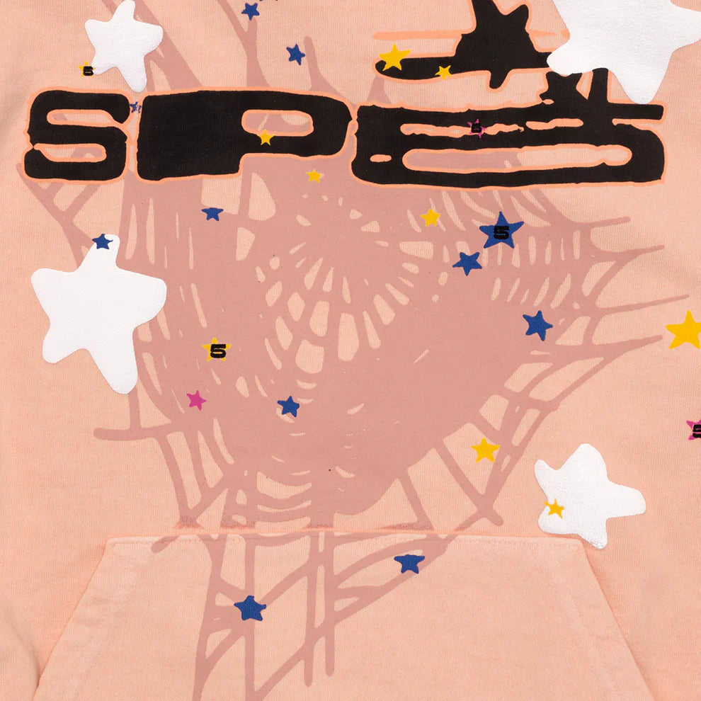The Sp5der Star Web Hoodie – Peach Pink 440GSM is a heavyweight oversized streetwear pullover featuring printed spiderwebs, scattered stars in white, blue, and yellow, bold black SPEC text, and a kangaroo pocket for classic Y2K style.