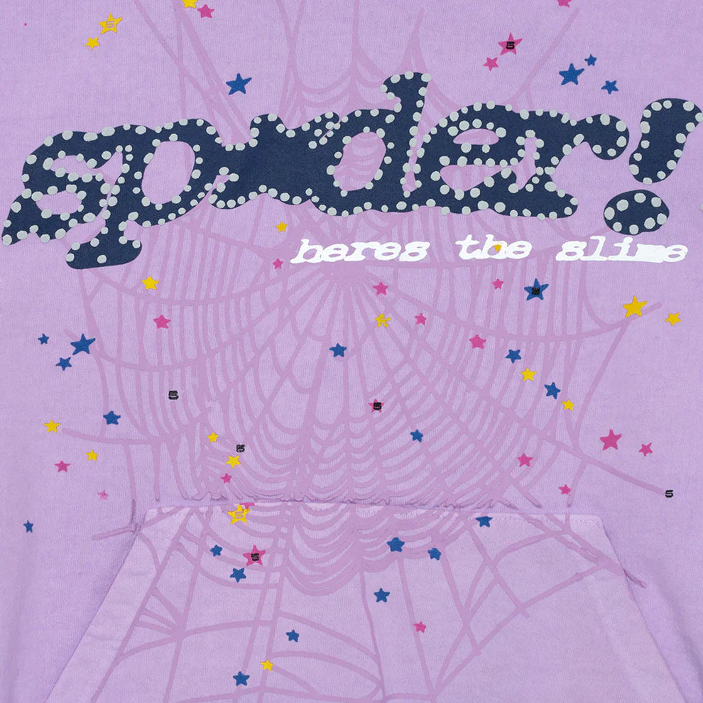The Sp5der “Hares the Slime” Hoodie is a lavender purple 440GSM heavyweight pullover featuring bold dotted “spider!” text, “heres the slime” in white, a faint spiderweb with colorful stars, and a classic streetwear pocket.