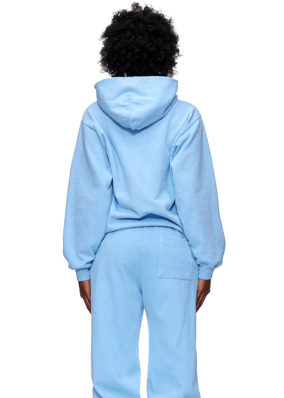 A person stands with their back to the camera, wearing a Sp5der Hoodie – Sky Blue 440GSM Heavyweight Chenille Logo Spider-Web Streetwear Pullover and matching sweatpants, hood up and arms at their sides for a classic streetwear vibe.