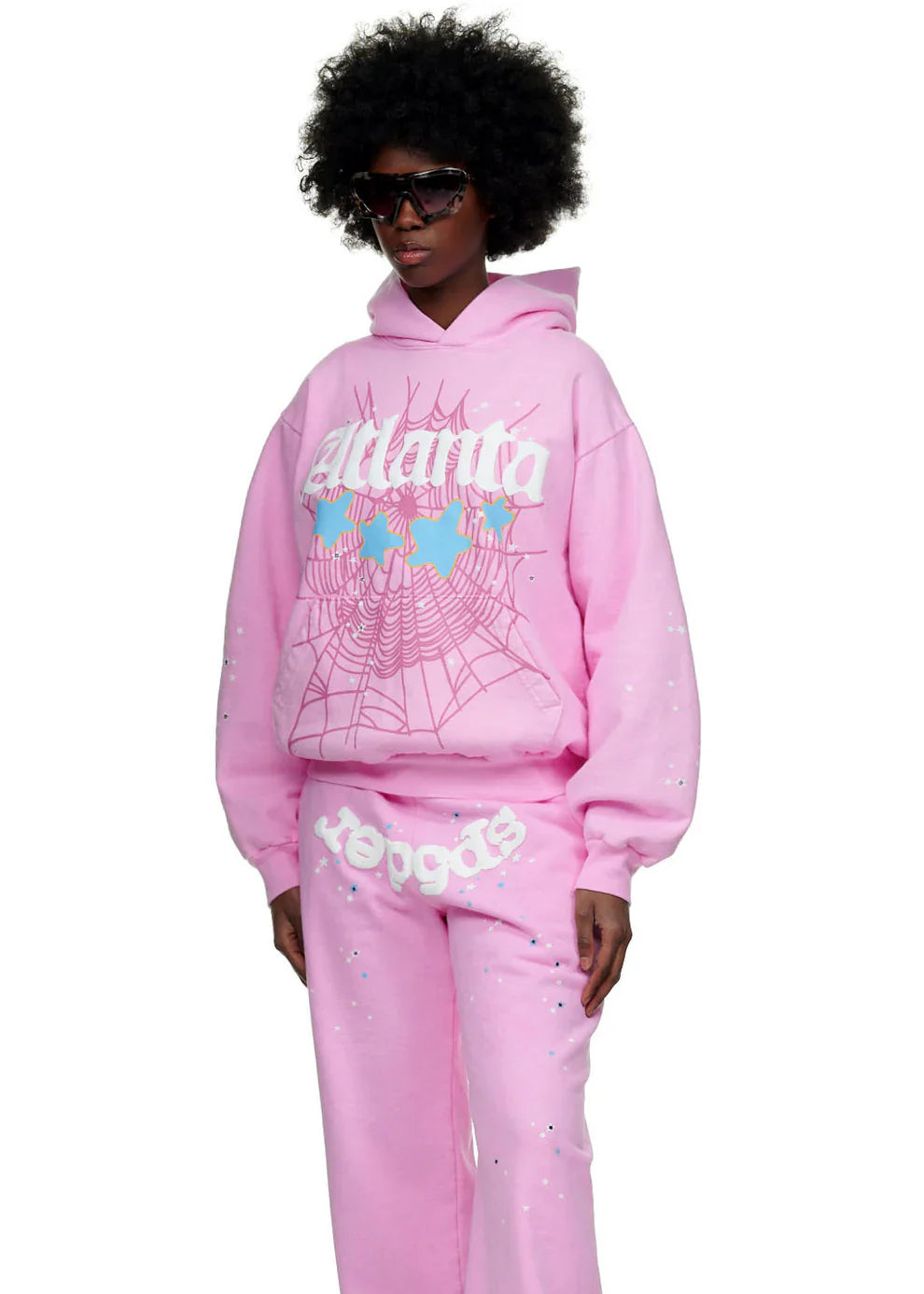 Wearing the Sp5der Atlanta Hoodie – Pink 440GSM Heavyweight Y2K Streetwear Pullover with matching sweatpants and bold shades, this look boasts white spiderweb prints, light blue details, and retro vibes for Y2K street style lovers.