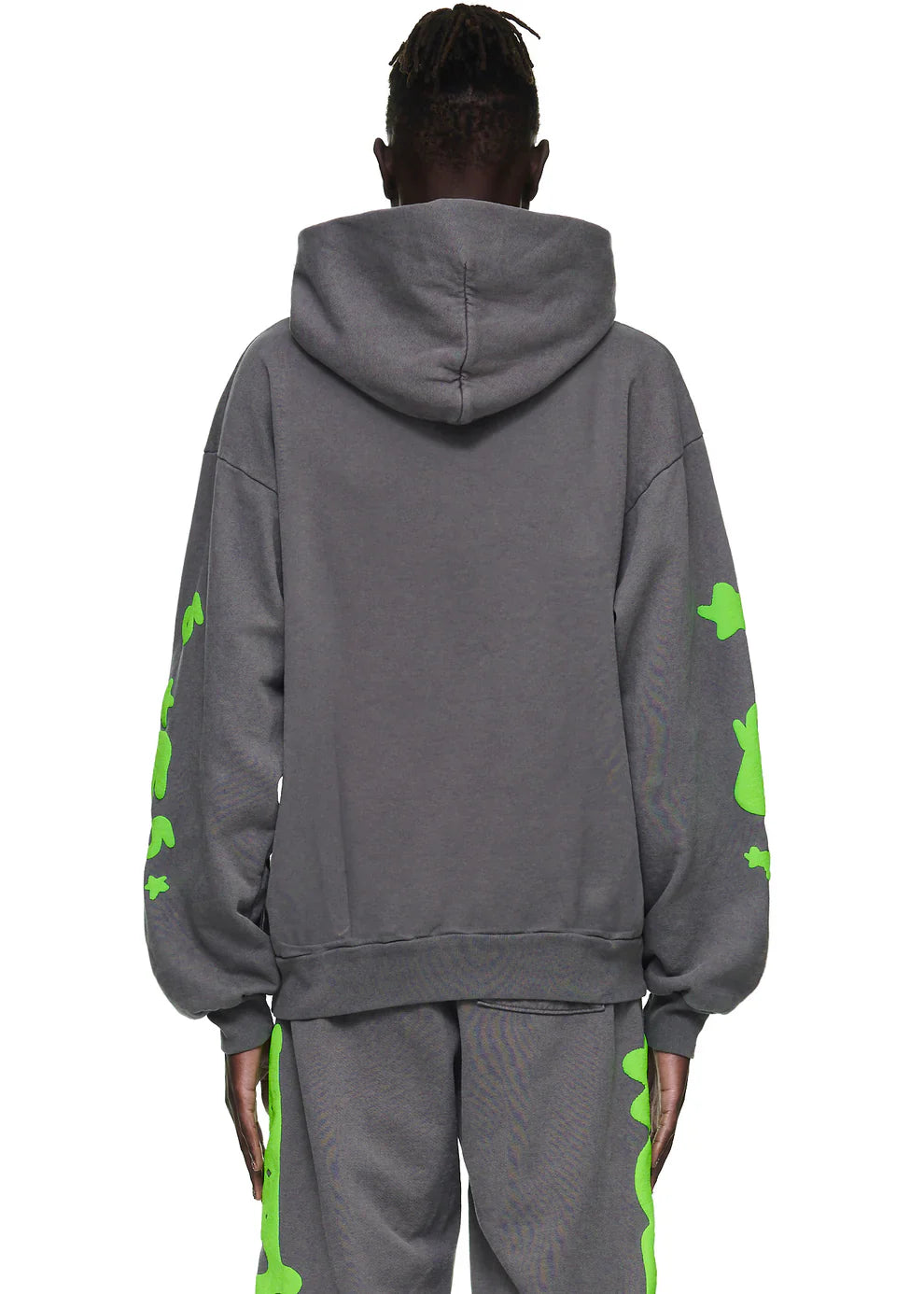 A person faces away from the camera wearing a Green and Grey Sp5der Hoodie—440GSM heavyweight, oversized, with bold bright green star graphics—showcasing standout streetwear style against a plain white background.