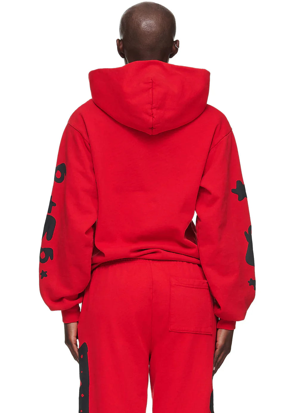 A person faces away, wearing the Sp5der “Starfire” Hoodie – Red & Black 440GSM Heavyweight Oversized Streetwear Pullover with black sleeve graphics and matching red pants. The hood is up, highlighting Y2K streetwear style and cozy comfort.