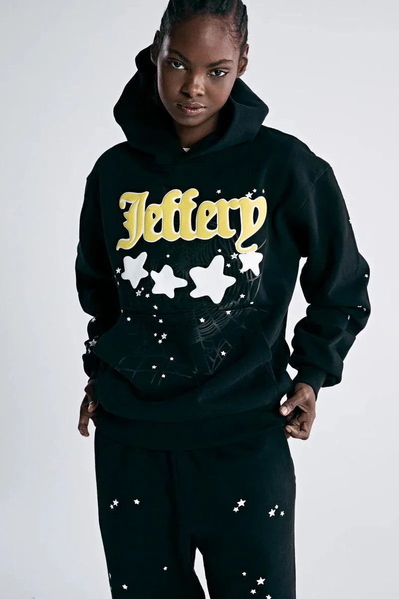 A person wears a Sp5der Jeffery Hoodie – Black Web 440GSM Heavyweight Streetwear Pullover, paired with matching black pants, standing against a plain light background.