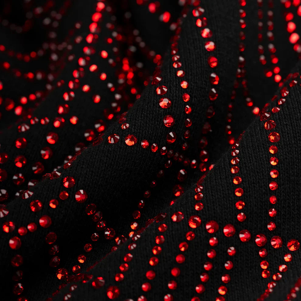 Close-up of the Sp5der Rhinestone Web Hoodie—Black 440GSM heavyweight cotton fleece—featuring wavy, shiny red rhinestones in a zigzag pattern, reflecting the bold, textured sparkle of luxury streetwear.