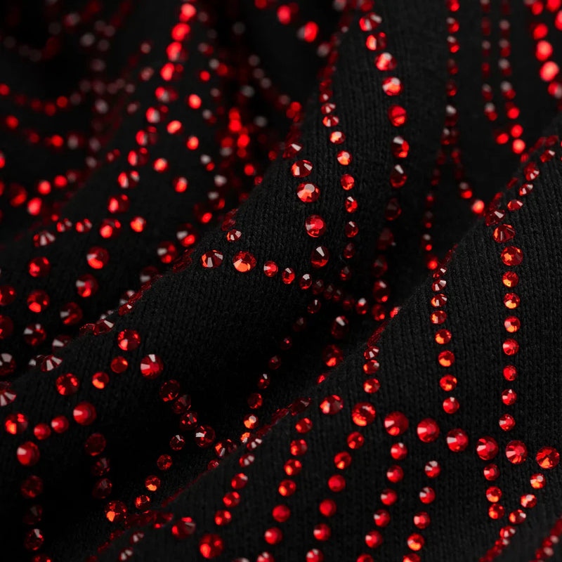 Close-up of the Sp5der Rhinestone Web Hoodie—Black 440GSM heavyweight cotton fleece—featuring wavy, shiny red rhinestones in a zigzag pattern, reflecting the bold, textured sparkle of luxury streetwear.