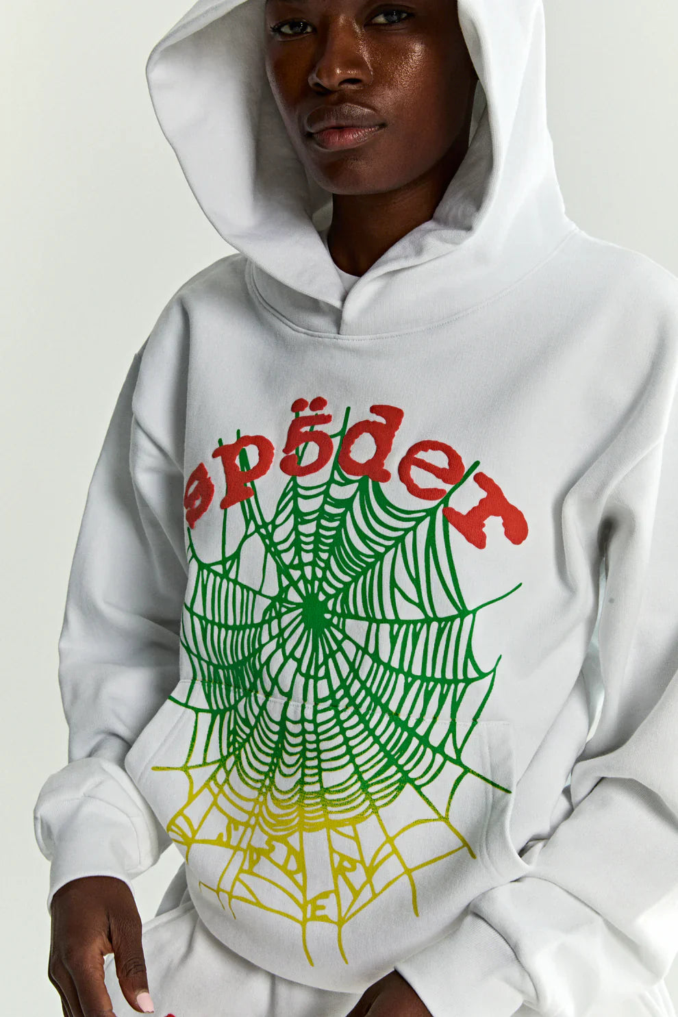 Wearing the Sp5der “Toxic Web” Hoodie—White & Neon Lime, a 440GSM heavyweight oversized streetwear pullover—a person stands with the hood up against a plain background.